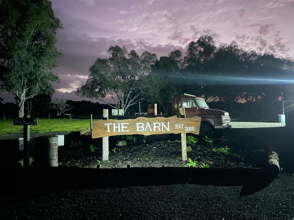 The Barn timber entry sign lit up at night