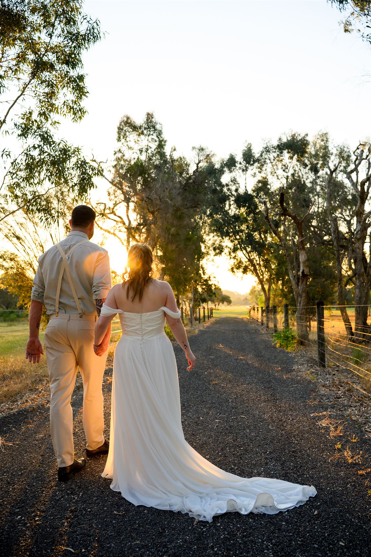 Newlyweds walking into the sunset down the farm road